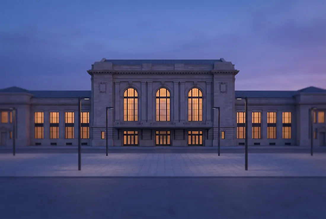 Stone railway station with tall arched windows lit warm at dusk, an empty plaza in front